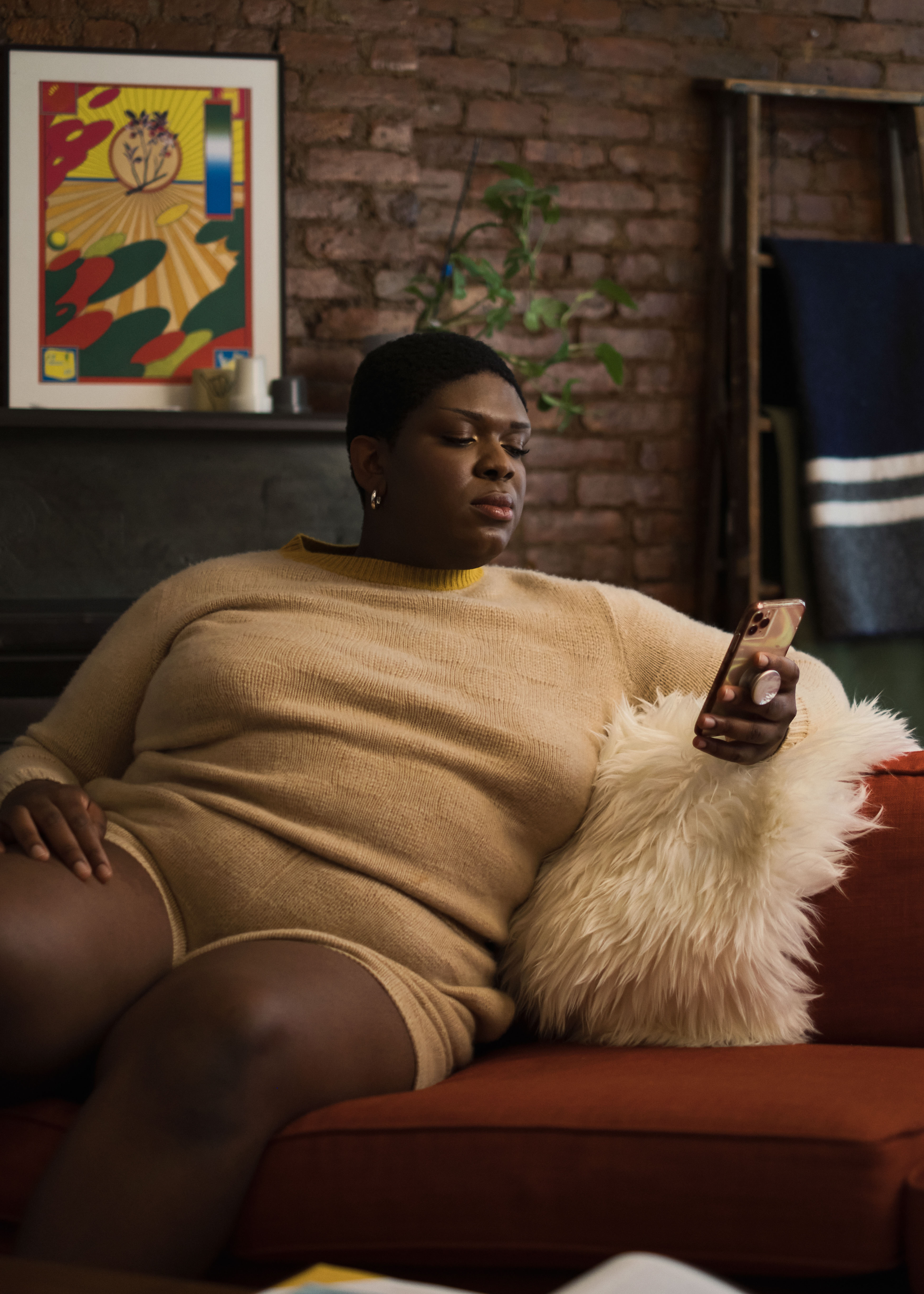 A non-binary trans woman using a cellphone in an apartment